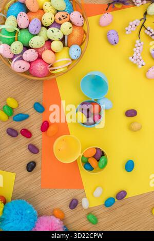 Bright background with candies in the form of Easter eggs in plastic eggs. Egg hunt concept. Happy Easter. Top view. Stock Photo