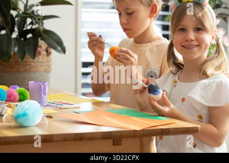 Children painting colorful easter eggs with joy and creativity at home. Easter Stock Photo