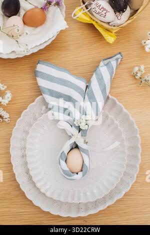 Easter egg wrapped in linen napkin in the shape of bunny with ears. Happy Easter Stock Photo