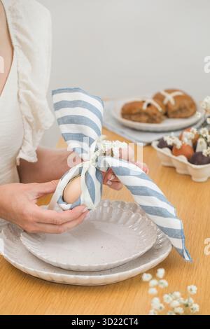 Woman decorating Easter table. Easter bunny made from egg and napkin. Happy Easter Stock Photo