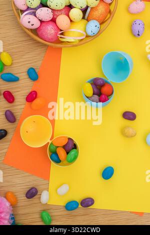 Bright background with candies in the form of Easter eggs in plastic eggs. Egg hunt concept. Happy Easter. Top view. Stock Photo