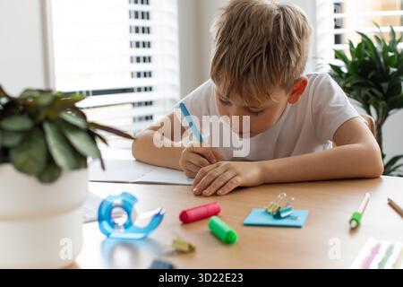 Cute boy doing school homework at home. Distance education. Online education. Stock Photo