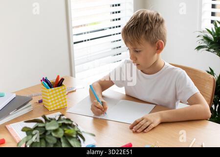 Cute boy doing school homework at home. Distance education. Online education. Stock Photo