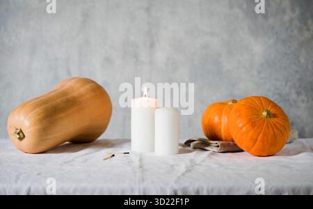Pumpkins and candles on a linen tablecloth. Stylish cozy autumn look. Autumn concept. Happy Thanksgiving. Copy space. Stock Photo