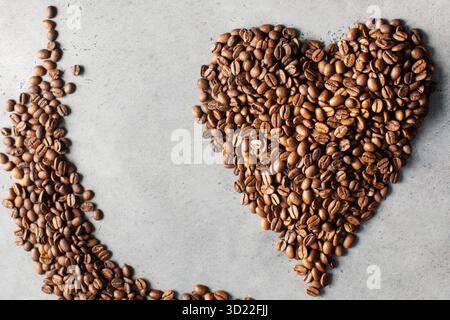 Coffee beans in the shape of a heart on a gray background. Stock Photo