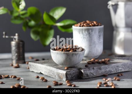 A handful of roasted coffee beans in bowl on a grey background. Stock Photo