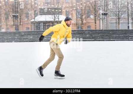 Bearded middle aged man on ice rink, outdoors in snowy winter day Stock Photo