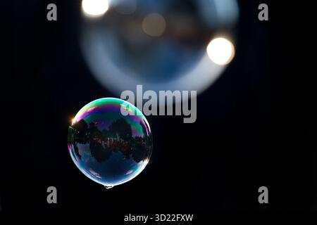 Two soap bubbles shimmering and floating in all colors against black background, Recklinghausen, North Rhine-Westphalia, Germany Stock Photo