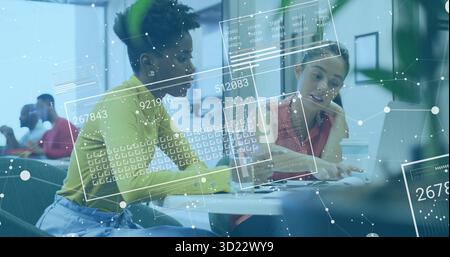 Collaborating two coworkers reviewing documents, typing on laptop in open-office with glass walls Stock Photo
