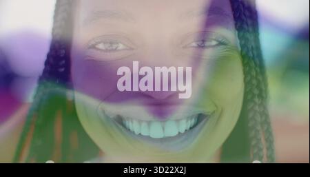 Smiling woman with braided hair showing colorful light patterns on face in studio, abstract art Stock Photo