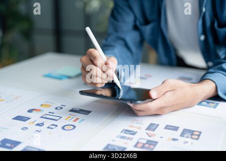 UX UI Designer Planning innovative Mobile App with Paper Wireframe Designs at Workspace. Stock Photo
