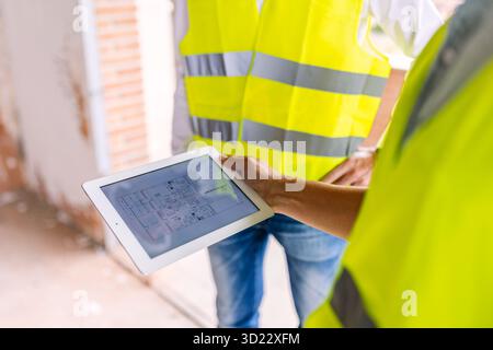 Engineers using digital tablet showing blueprint at construction site Stock Photo