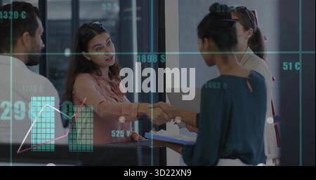 Two women in business suits shaking hands in lobby with clipboard laptop and digital charts Stock Photo