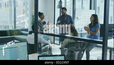 Coworkers collaborating at conference room table, with tablet laptop and digital overlay graphics Stock Photo
