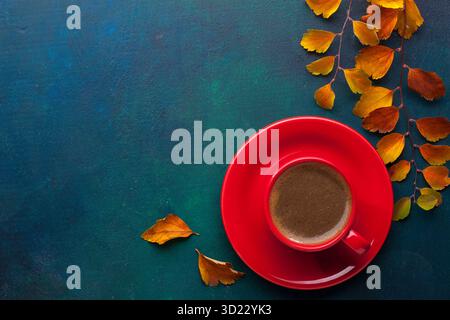 Cup of black coffee and branches of autumn leaves (Spiraea Vanhouttei)  on a dark blue-green painted wooden table. Flat lay Stock Photo