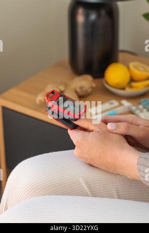 Caucasian female using red pulse oximeter on finger for health monitoring at home Stock Photo