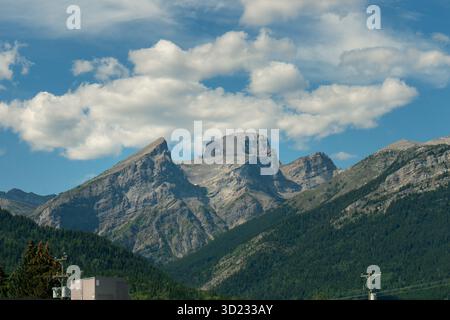 Majestic rocky mountains against a vibrant blue sky dotted with white clouds. Fernie, BC Stock Photo