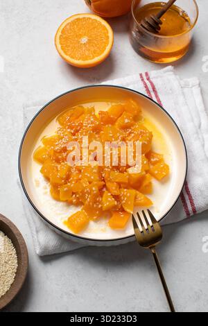 Fresh mango salad with honey and sesame garnished in a white bowl on a light background Stock Photo