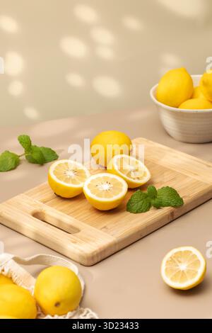 Whole and halves of yellow lemons on a wooden board. Juicy ripe lemons. Stock Photo