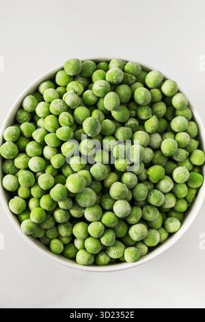 A bowl of frozen green peas on a white background. Fresh and healthy vegetable Stock Photo