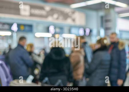 Blurry image of diverse adults in busy airport with signs and lights Stock Photo