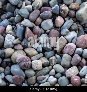 Smooth multicolored pebbles in shades of grey, brown, and blue arranged closely. Waterton Park, Alberta, Canada Stock Photo