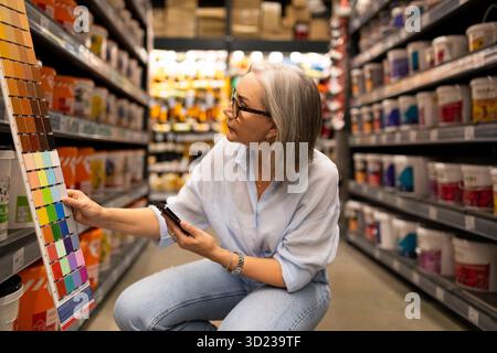 Engaging woman in a modern warehouse selecting paint colors for home improvement projects Stock Photo