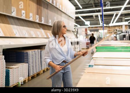 Woman shopping for home improvement materials in a retail store with various departments focused on kitchen and garden needs Stock Photo