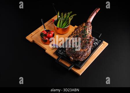 Delicious grilled tomahawk steak served with veggies on wooden platter Stock Photo