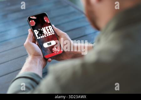 Man playing online poker on mobile phone outdoors, closeup Stock Photo