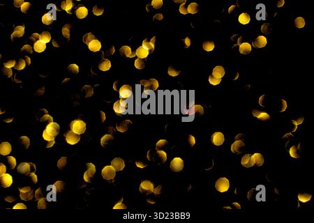 Golden bokeh lights against black background creating a warm and festive Stock Photo