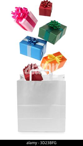 Many gift boxes falling into paper bag on white background Stock Photo