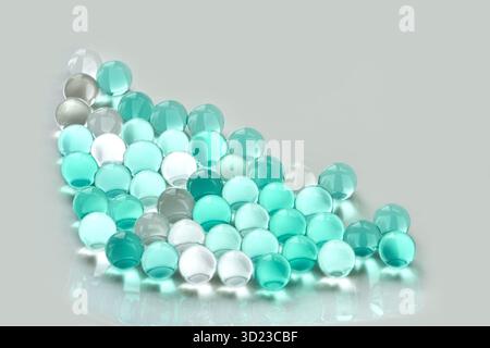Arrangement of translucent aqua and white marbles on reflective surface Stock Photo