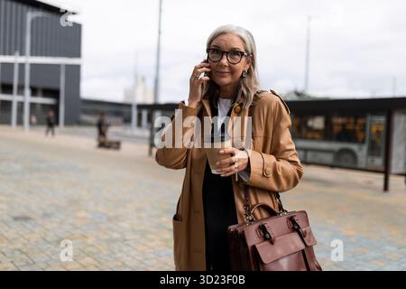 Caucasian senior businesswoman talking on mobile phone outside Stock Photo