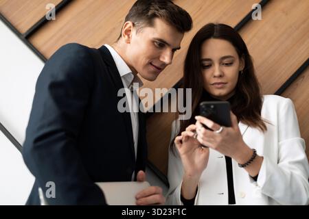 Colleagues man and woman communicate during a break demonstrating a mobile phone Stock Photo
