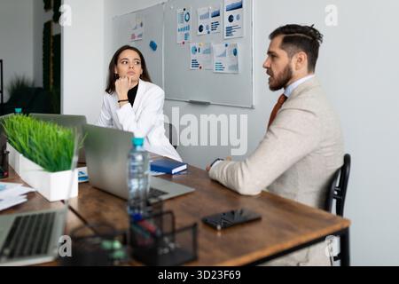 Businessmen at a large desk in a meeting room during a rally Stock Photo