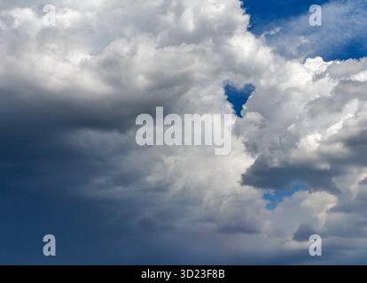 Fluffy white and gray clouds against a bright blue sky. Stock Photo