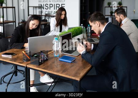 Working days in the office employees sit in open space and work on laptops and phones in business clothes multinational colleagu Stock Photo