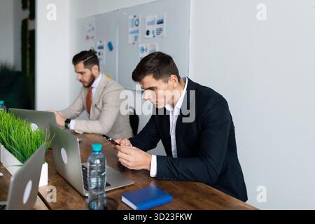 Serious business people at the meeting look at the screens of mobile phones Stock Photo