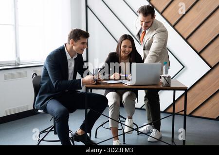 Interaction of office employees during the working day at the table in front of a laptop Stock Photo