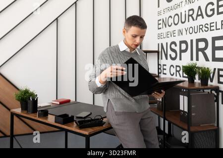 Business woman reading a report in a leather folder on the desktop in the office Stock Photo