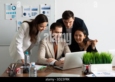 Charming employees in the office At the laptop, colleagues look at the screen with delight Stock Photo