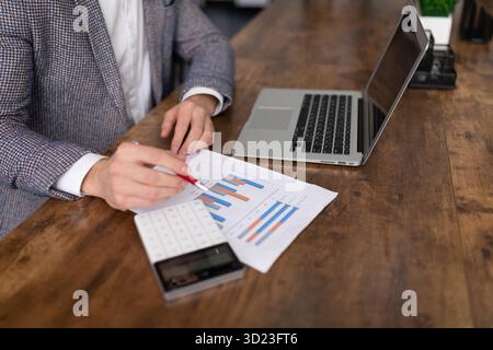 Sales specialist calculates profit using laptop and calculator Stock Photo