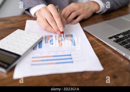 Business graph on paper close up on desk in office with laptop and calculator Stock Photo