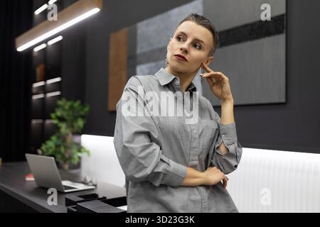Confident modern woman head in a sterile office stands thinking Stock Photo