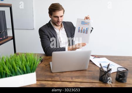 Manager in a business suit demonstrates a schedule while communicating via video link using a laptop Stock Photo