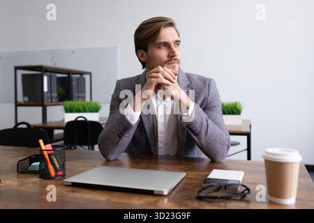 Stylish young businessman pensive sitting at the table in the office Stock Photo