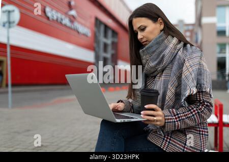 Young woman working with a laptop in her hands next to an office building Stock Photo