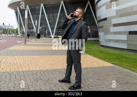 Adult male entrepreneur talking on the phone against the background of a non-business center Stock Photo