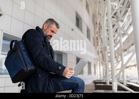 Businessman at the airport waiting to board the plane working online on a laptop Stock Photo